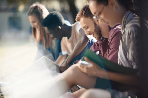 selective focus of happy multicultural students studying with books in park